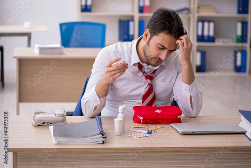 Young male employee suffering at workplace photo