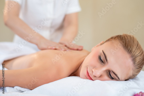 Beautiful young attractive Caucasian woman having body massage by Thai Masseur in spa salon. Beauty treatment and body care lifestyle concept