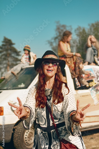 Middle-aged woman in hippie dress shows hands hipster peace sign