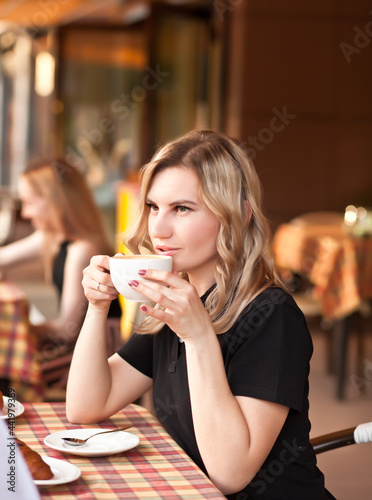 Young woman drinking a coffee in a cafe terrace with friends