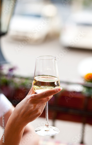 Woman holding a glass with white wine in a cafe