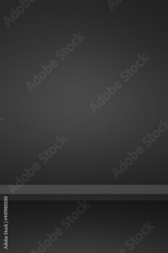 Empty shelf on a black wall. Background template. Vertical backdrop