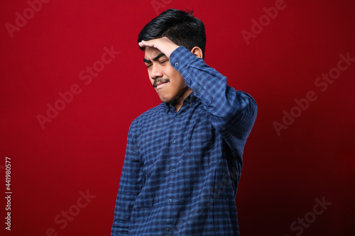 Young handsome asian man wearing casual shirt hand on head for pain in head because stress. Suffering migraine.