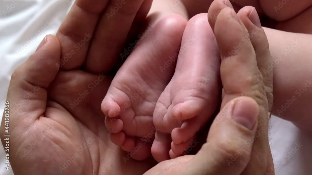 Father holding Baby Feet in Hands. Legs Newborn in male parents Hand. Small children's Feet in the Father's Palm. Close-up. Little Toes of Child and Man Hands of Happy Parent. Father's Day Holiday. Father holding Baby Feet in Hands. Legs Newborn in male parents Hand. Small children's Feet in the Father's Palm. Close-up. Little Toes of Child and Man Hands of Happy Parent. Father's Day Holiday.