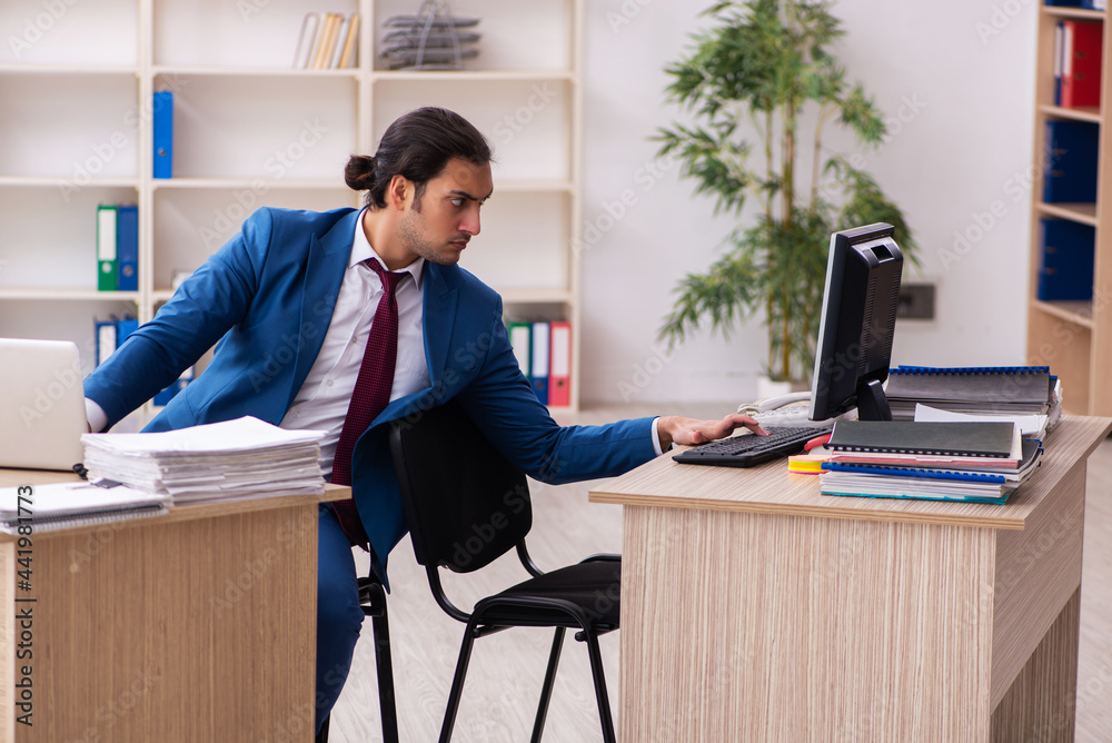 Young male employee in multitasking concept Young male employee in multitasking concept