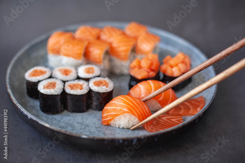 Traditional japanese nigiri sushi with salmon placed between chopsticks