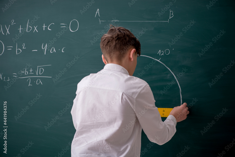 Schoolboy studying geometry in front of blackboard Schoolboy studying geometry in front of blackboard