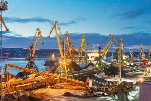 Twilight. Heaps of coal in the seaport. Coal is unloaded from wagons by all kinds of cranes, then loaded into the holds of sea ships.