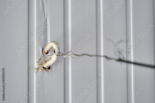 White colored hook and tied with metal wire on in with white background.