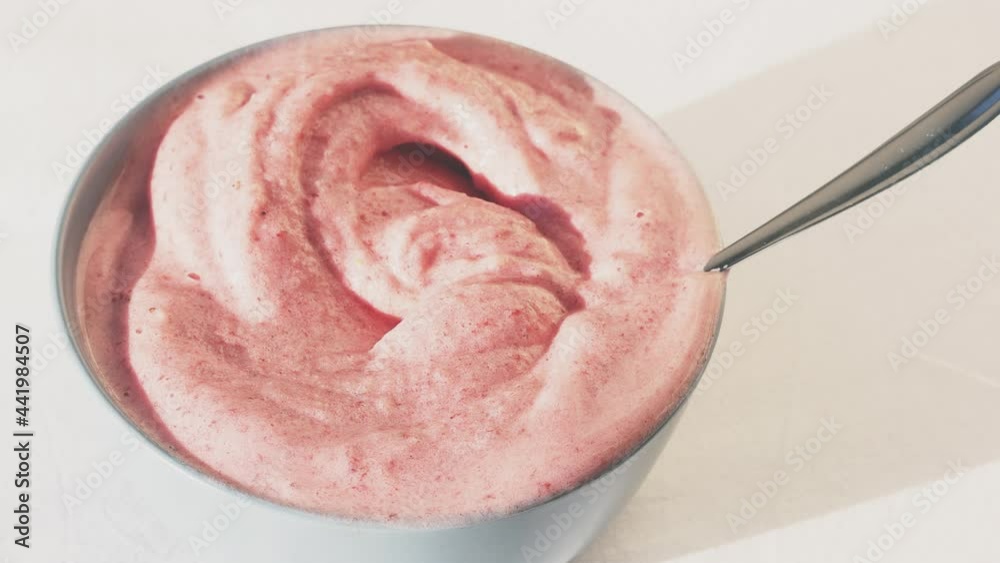 Berry smoothie whipped with a blender and laid out in a bowl. Vegan product. The pink ice cream is shaken with a spoon. Berry smoothie whipped with a blender and laid out in a bowl. Vegan product. The pink ice cream is shaken with a spoon.