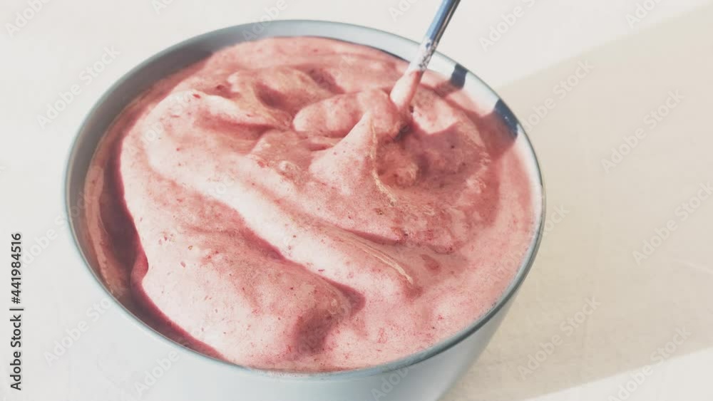 Berry smoothie whipped with a blender and laid out in a bowl. The pink ice cream is mixed with a spoon. Vegan product. Berry smoothie whipped with a blender and laid out in a bowl. The pink ice cream is mixed with a spoon. Vegan product.