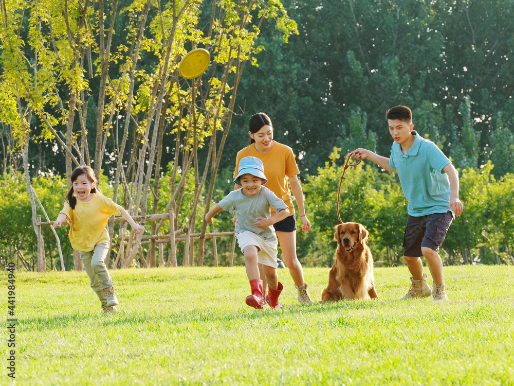 Obraz premium Happy family of four and pet dog playing in the park