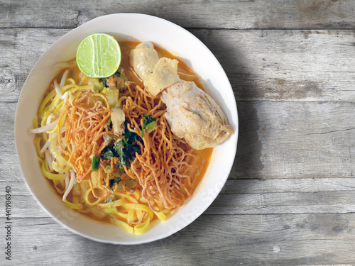 bowl of chicken khao soi. Northern Thai food noodle on wooden background. photo