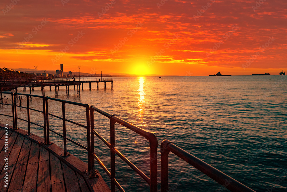 Obraz premium Sunset in Cyprus. View from the Limassol embankment. Sun sets in Mediterranean. Limassol at sunset. Seascape of Cyprus. Evening Limassol. Mediterranean evening landscape. Holidays in Cyprus.