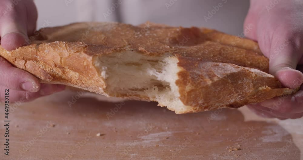 Close up of baker hands breaking homemade bread Close up of baker hands breaking homemade bread