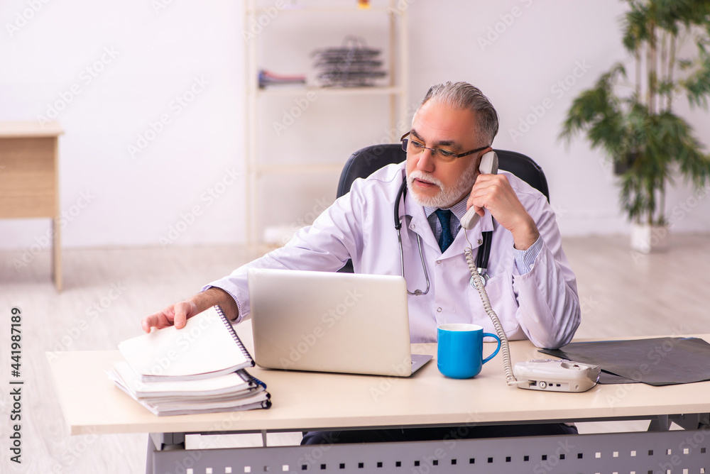 Aged male doctor working in the clinic