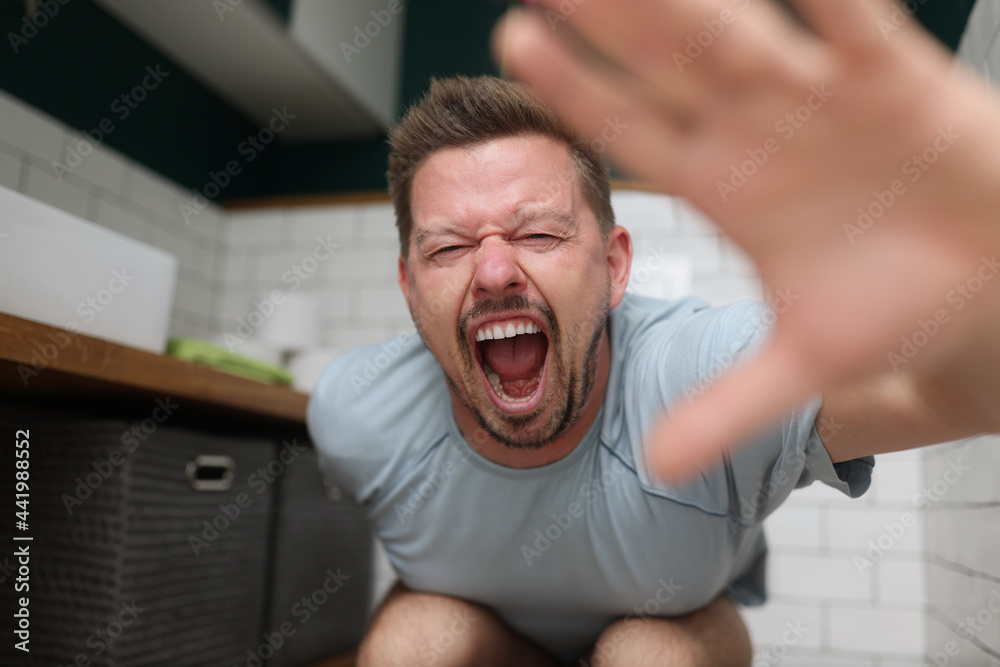 Man sitting on toilet and screaming in pain Stock Photo Adobe Stock