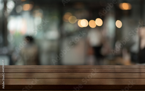 Empty wooden table top with lights bokeh on blur restaurant background.