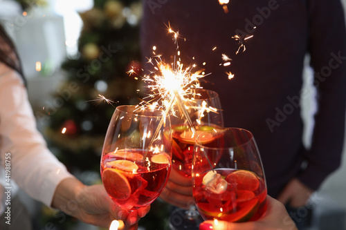 Group of people holding glasses with cocktails and sparklers closeup