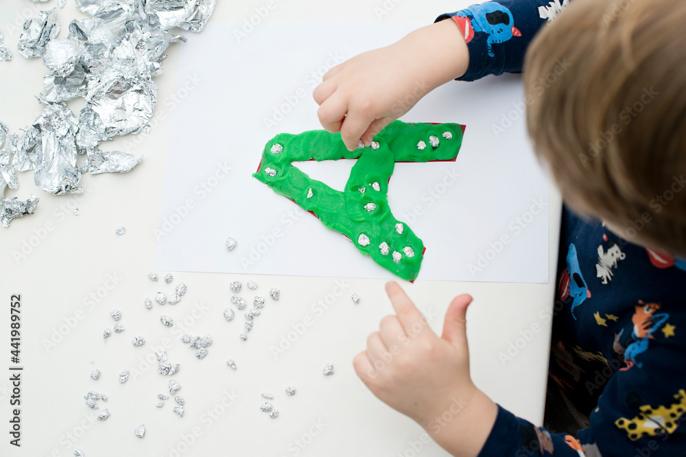 Fototapeta premium Two year boy decorating play dough letter 