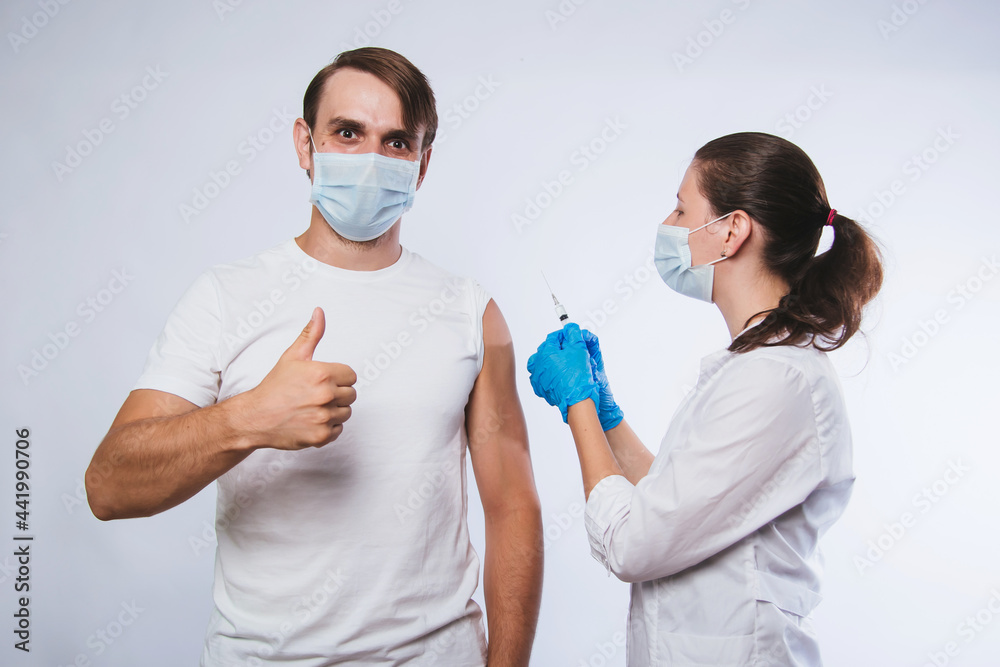 Girl doctor holds a syringe and makes an injection to a patient in a medical mask. Covid-19 or coronavirus vaccine. Masked man receiving coronavirus vaccination graft