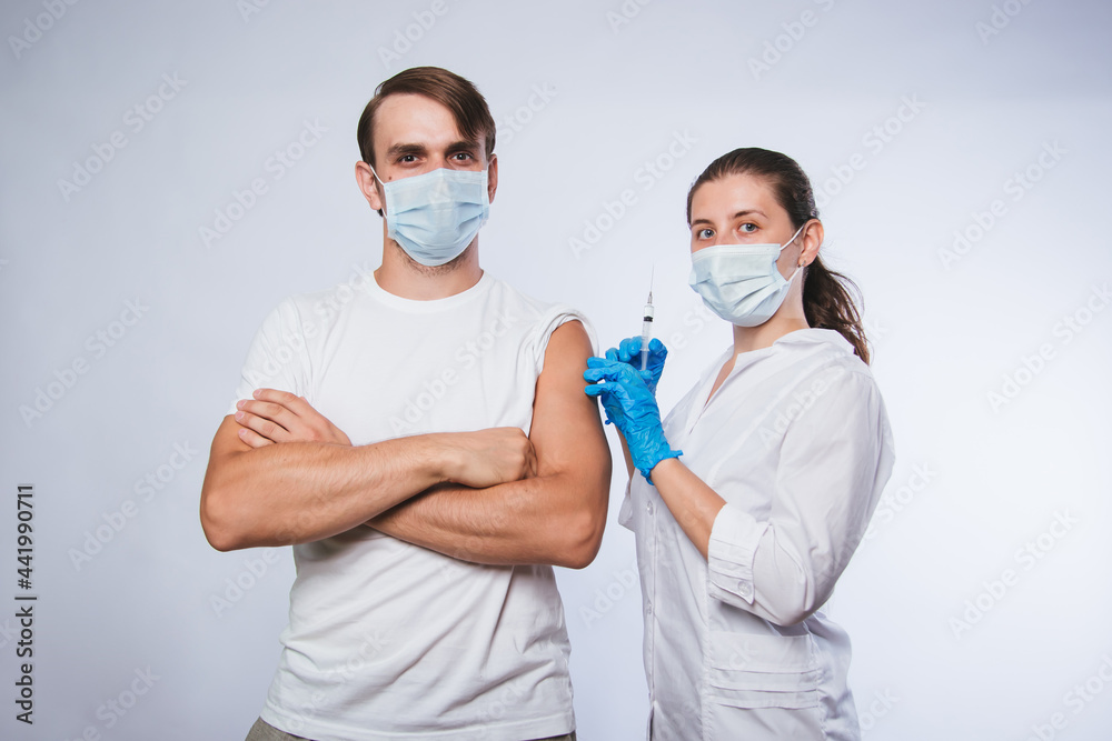Girl doctor holds a syringe and makes an injection to a patient in a medical mask. Covid-19 or coronavirus vaccine. Masked man receiving coronavirus vaccination graft