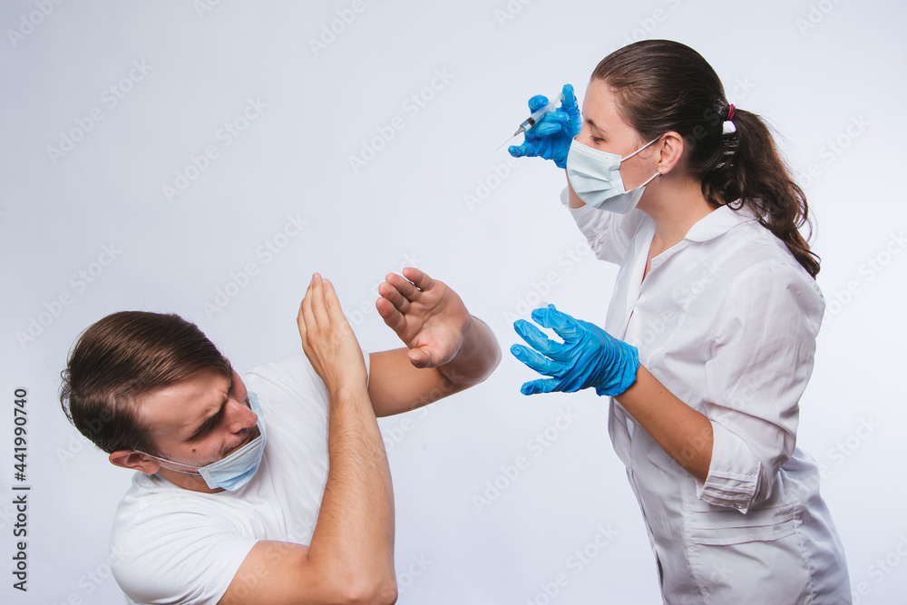© Вероника Преображенс - People vaccination phobia concept. A female doctor is trying to vaccinate a frightened male patient. The mistrustful patient, the anti-inoculant refuses to take it. Stop vaccination. © Вероника Преображенс - People vaccination phobia concept. A female doctor is trying to vaccinate a frightened male patient. The mistrustful patient, the anti-inoculant refuses to take it. Stop vaccination.