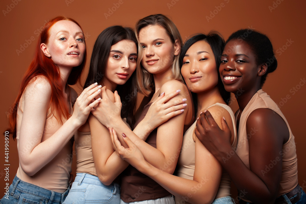 Obraz premium young pretty asian, caucasian, afro woman posing cheerful together on brown background, lifestyle diverse nationality people concept