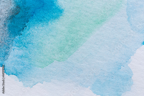 Macro close-up of an abstract blue, light blue and turquoise watercolor gradient fill background with watercolour stains. High resolution full frame textured white paper background.