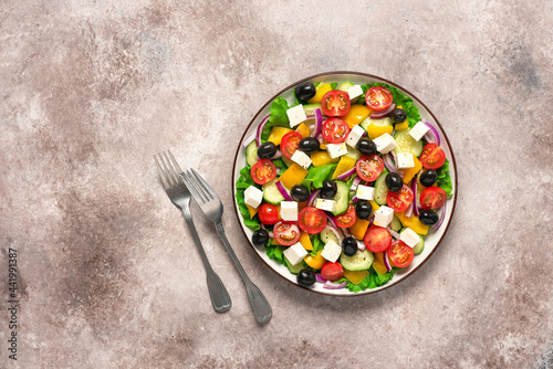 Greek salad on a brown grunge background. Top view, flat lay.