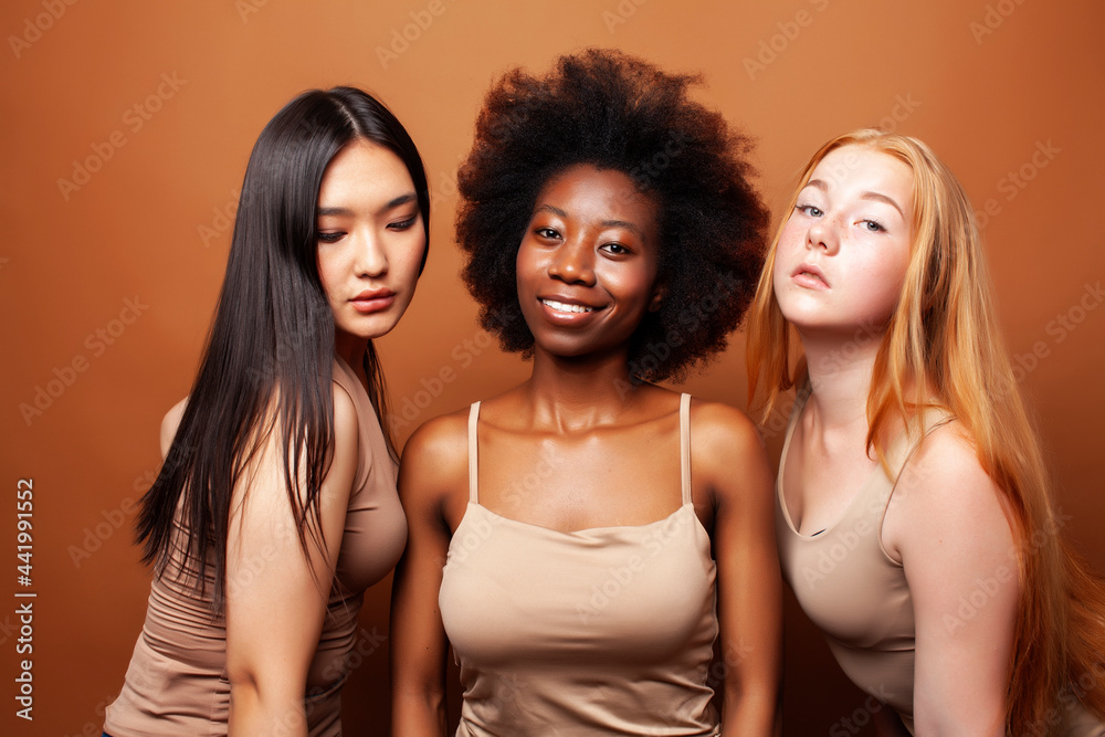 young pretty asian, caucasian, afro woman posing cheerful together on brown background, lifestyle diverse nationality people concept young pretty asian, caucasian, afro woman posing cheerful together on brown background, lifestyle diverse nationality people concept