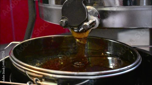 Honig fließt aus der Honigschleuder, Waldhonig und Blütenhonig dunkel golden aus dem Auslass