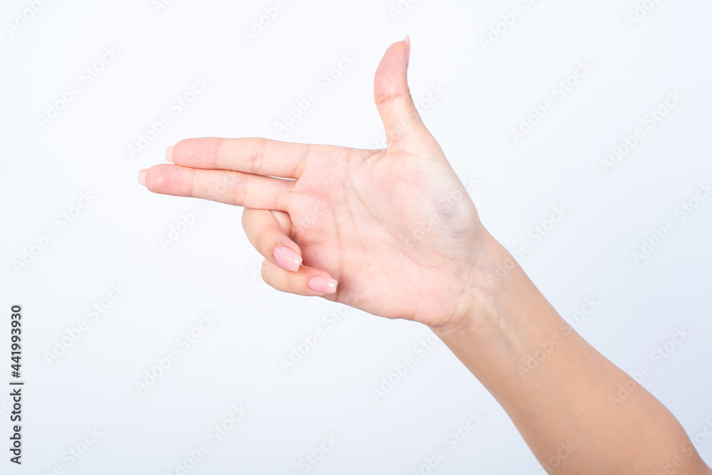 Woman's hand with pink manicure over isolated white background pointing aside or making gunfire gesture