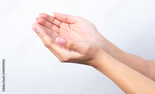 Woman's hand with pink manicure over isolated white background putting hands as receiving something or praying making douas