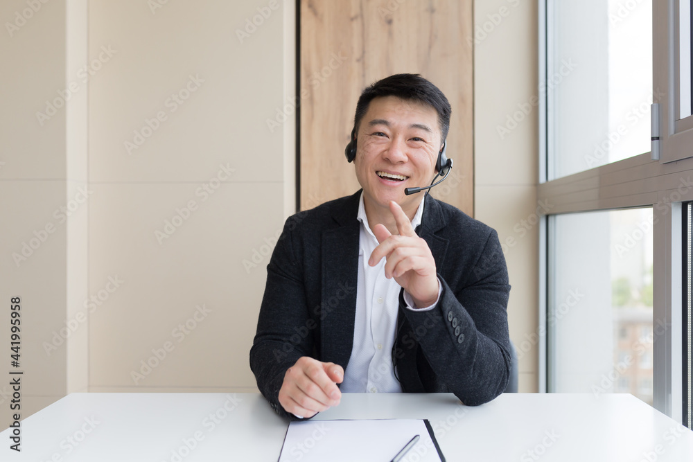 Male businessman conducts an online consultation explains cheerfully gestures with his hands using a headset, and online call Male businessman conducts an online consultation explains cheerfully gestures with his hands using a headset, and online call