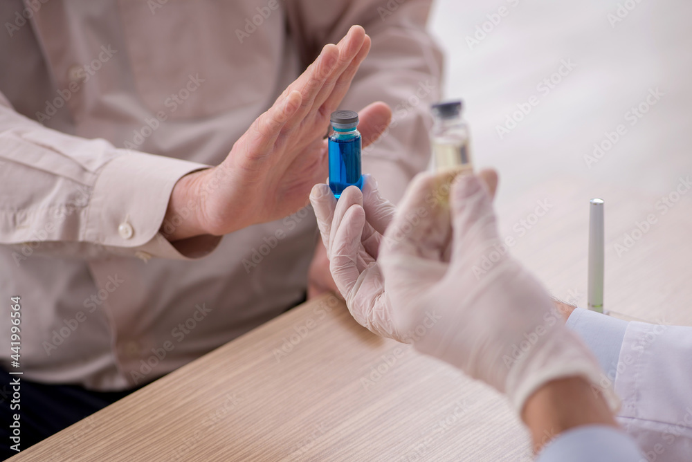 Old male patient visiting young male doctor in vaccination conce Old male patient visiting young male doctor in vaccination conce