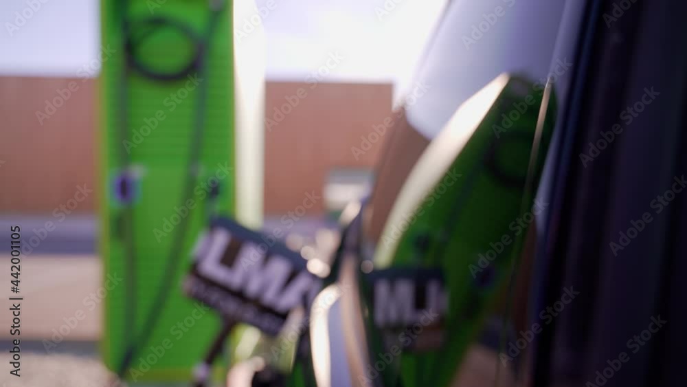 Elektroauto steht an der Tankstelle bzw. Aufladestation für Elektroautos und Hybridfahrzeuge und lädt die Akkus mit Strom aus umweltfreundlicher erneuerbarer Sonnenenergie auf. 