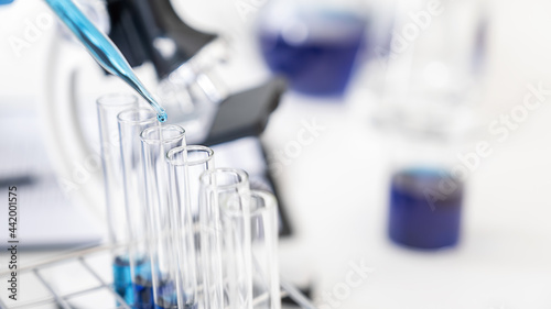 Scientist dropping a sample into a test tube with dropper in pharmaceutical research laboratory. Innovation Concept.