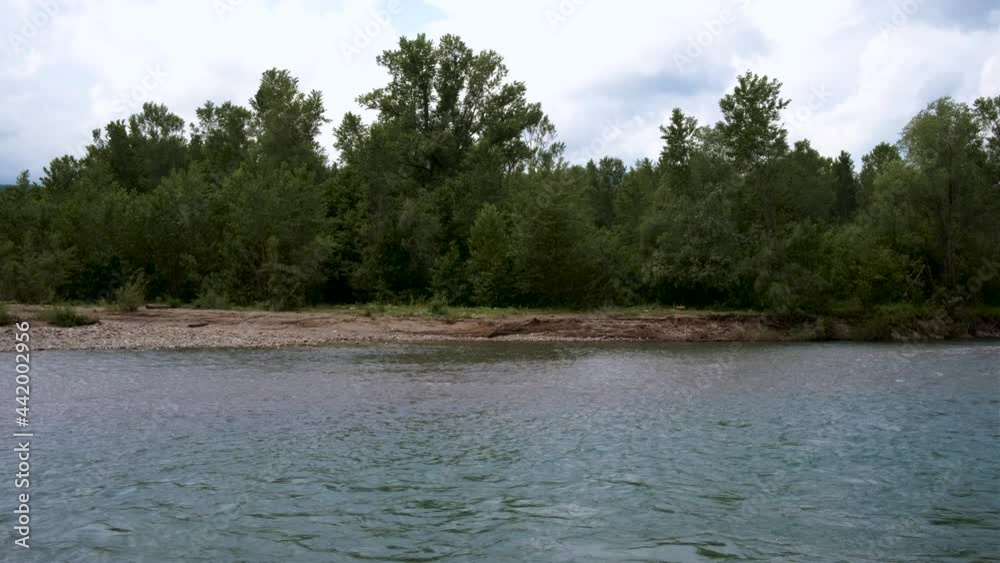Beautiful calm mountain river of bluish hue flows slowly among stones against background of green dense summer forest. Mountain river fascinates and attracts attention. Horizontal 4k real time video. Beautiful calm mountain river of bluish hue flows slowly among stones against background of green dense summer forest. Mountain river fascinates and attracts attention. Horizontal 4k real time video.