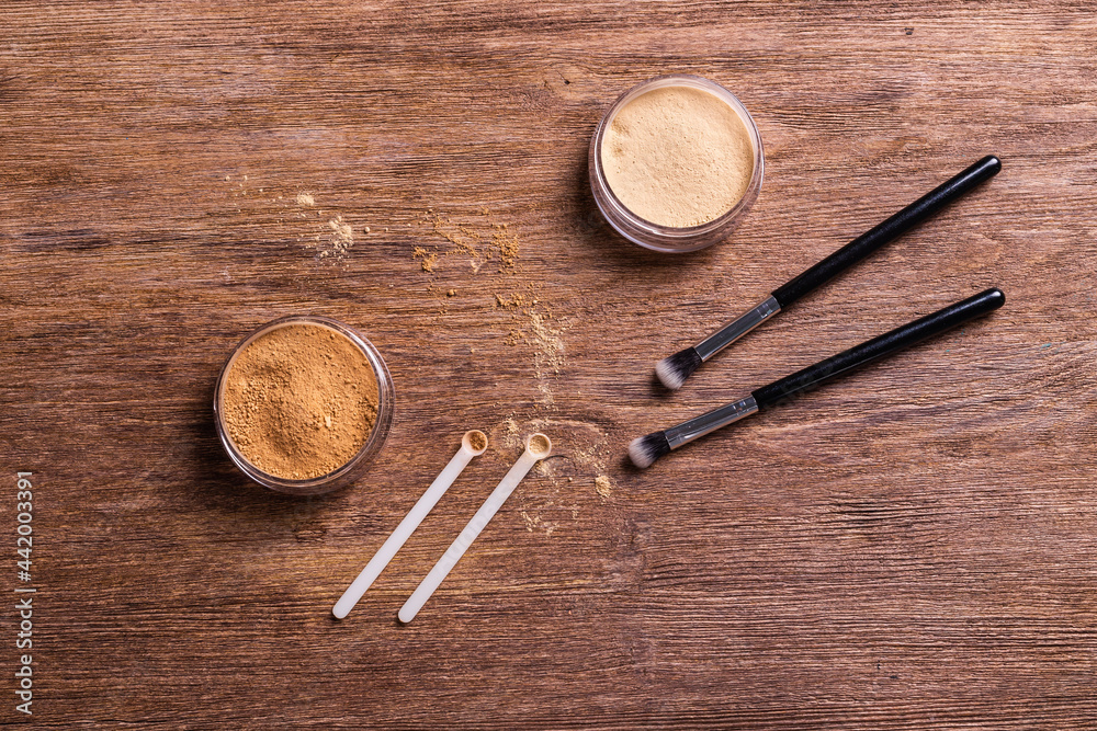 Mineral powder foundation with brushes on a wooden background. Eco-friendly and organic beauty products Mineral powder foundation with brushes on a wooden background. Eco-friendly and organic beauty products