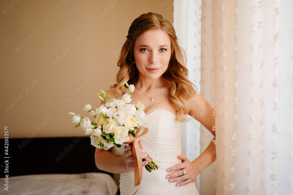 portrait of a beautiful bride with a bouquet by the window. Wedding traditions.