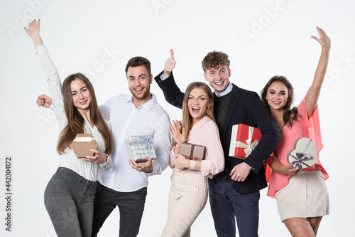 Portrait of excited young beautiful happy people feeling happy standing isolated on white, holding boxes in wrapping paper.