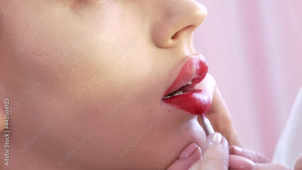 Bright lip makeup, big beautiful lips are painted with red lipstick with a special brush in a beauty salon. Professional make-up Bright lip makeup, big beautiful lips are painted with red lipstick with a special brush in a beauty salon. Professional make-up