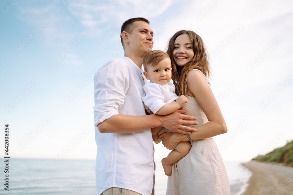 Young family on the beach. People are having fun on summer vacation. Father, mother and child against the background of the blue sea and sky. Travel, active lifestyle, vacation, rest concept. Young family on the beach. People are having fun on summer vacation. Father, mother and child against the background of the blue sea and sky. Travel, active lifestyle, vacation, rest concept.