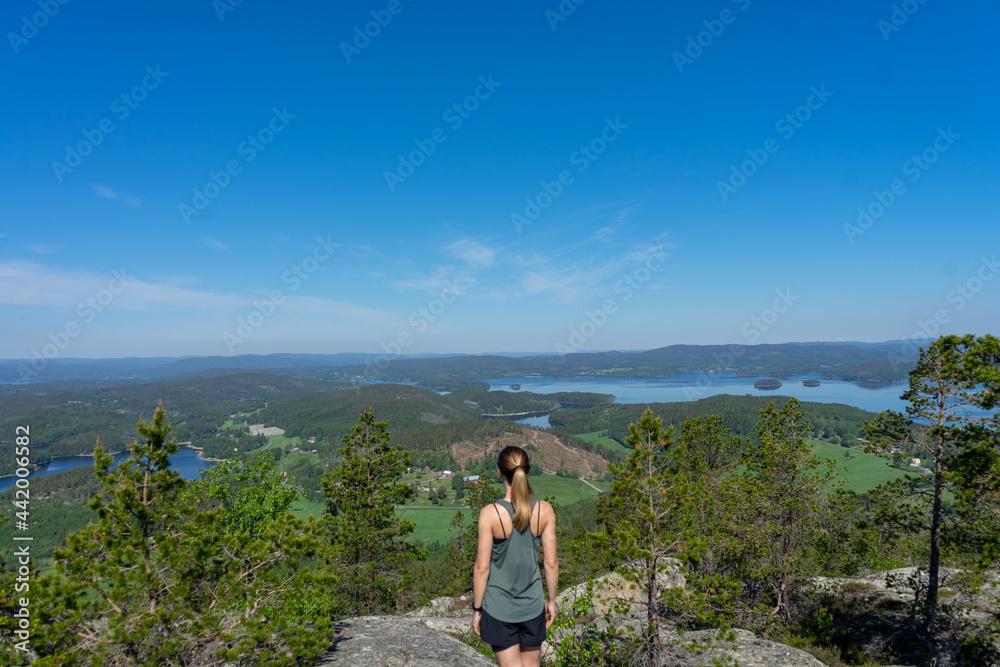Naklejka premium Girl wearing green top looking out over the landscape of the High Coast, Vasternorrland, Sweden