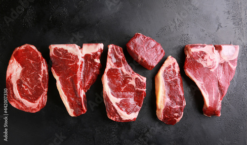 Assorted raw meat steaks. Japanese marble wagyu meat on a black table. Background image, copy space. Top view, flatlay