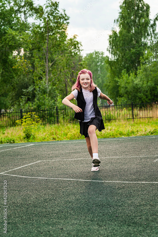 A girl in a school uniform with pink hair runs through the school playground. Warm-up, daytime, open air