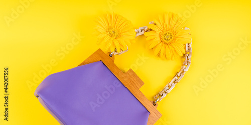 Purple fashion lady handbag with gerbera daisy flowers on yellow background