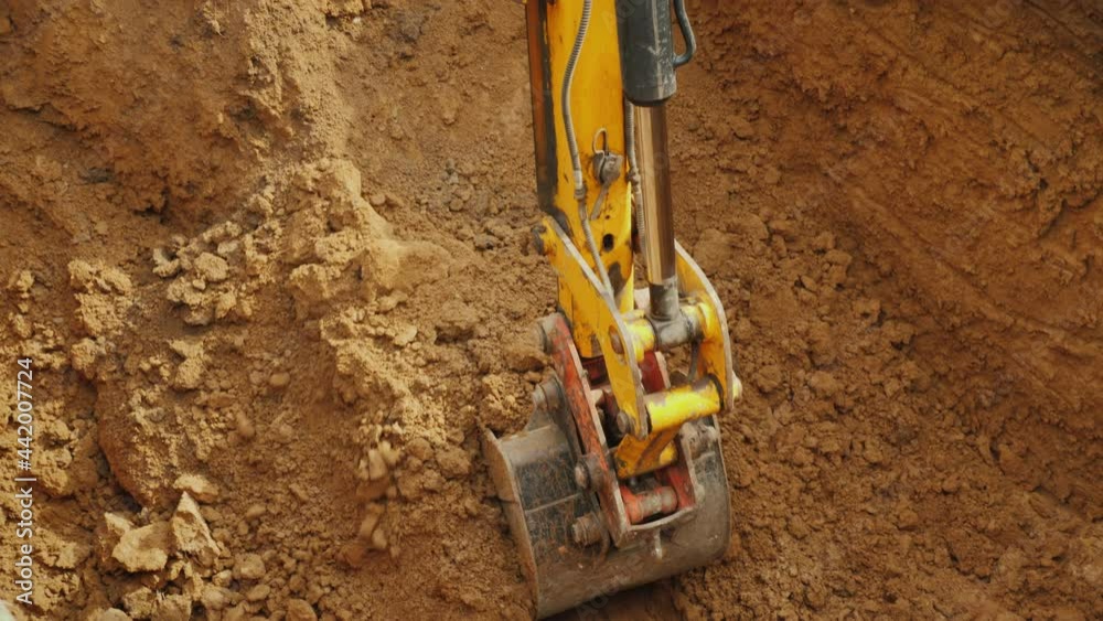 Large digger bucket extracts soil from trench