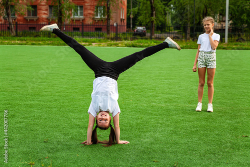 The girl is engaged in acrobatics in the stadium. Warm-up, stand-up, child, street, day